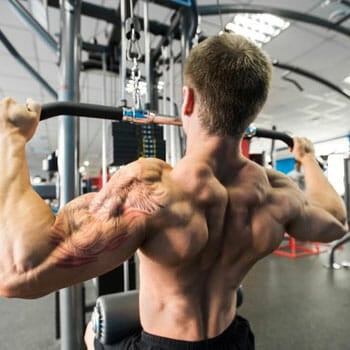 shirtless man working out in a lat machine