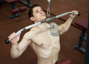 shirtless man in a wide grip lat pulldown position