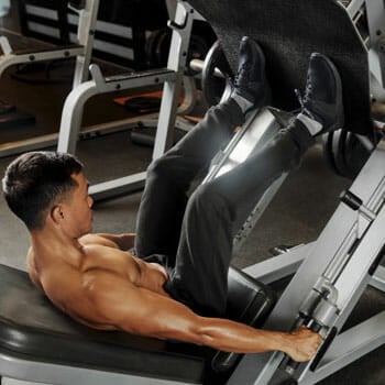 shirtless man using a leg press in a gym