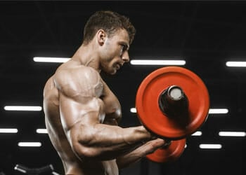 shirtless man using a heavy barbell inside a gym