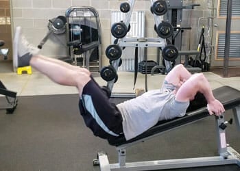 man in an incline leg lift position in a gym