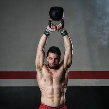 shirtless man doing kettle swings