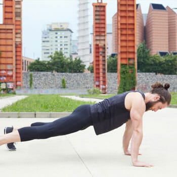 man in a pushup position in a park