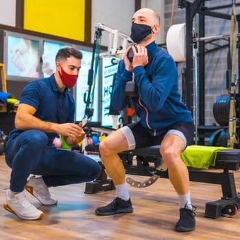 instructor teaching a man how to squats