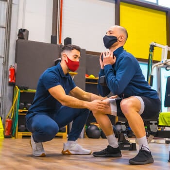 trainer teaching a man how to do squats