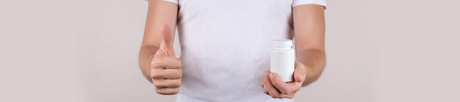 man in a white shirt holding up a pill container and a thumbs up