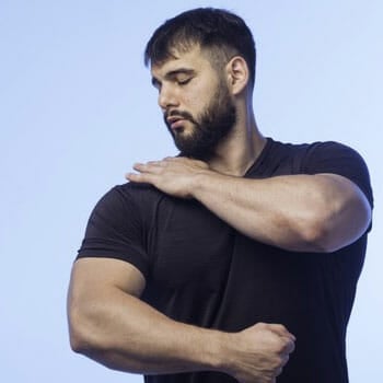 man in a black shirt touching and looking at his shoulder