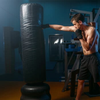 shirtless man punching a standing heavy bag