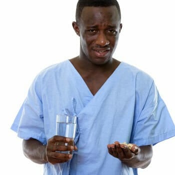 male nurse disgust face while raising up medicine pills and a glass of water