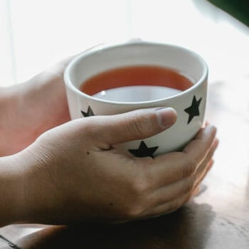 a cup of hot tea wrapped in woman's hands