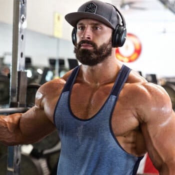 bradley martyn wearing a blue muscle top working out inside a gym