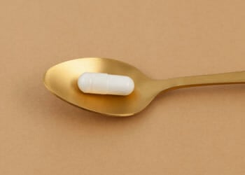 a white pill on top of a gold spoon