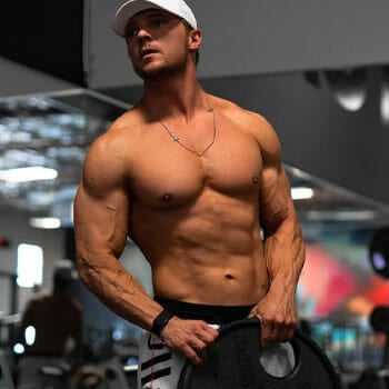 shirtless Steve Cook carrying a barbell plate