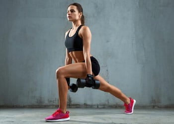 woman in a lunge position holding dumbbells