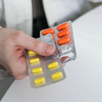 close up image of a person holding sachets of pills