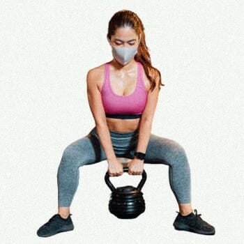 A woman holding a kettlebell with both hands