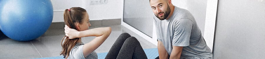 A girl doing crunches with her coach