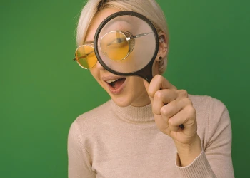 Woman holding a magnifying glass to show her skin