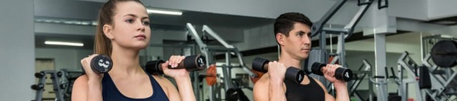 man and woman working out using dumbbells in a gym