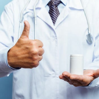 medical personnel raising a thumbs up and a bottle of pills