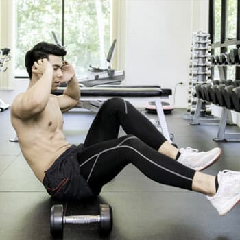 shirtless man doing ab exercises in a gym