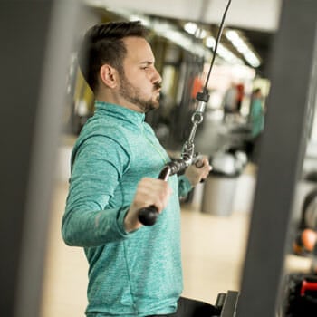 man using a lat machine inside a gym