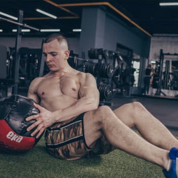 shirtless man using a medicine ball for russian twists
