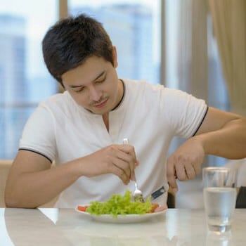 man seated in a kitchen table eating