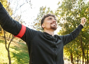 man raising his arms in happiness outdoors