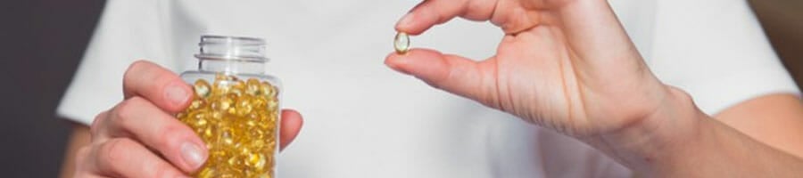 man holding both bottle and capsule of fish oil