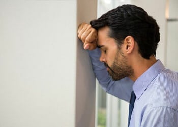 man worrying while leaning towards a wall