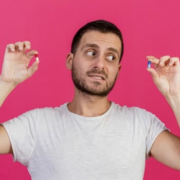 man in a white shirt holding up two different pills