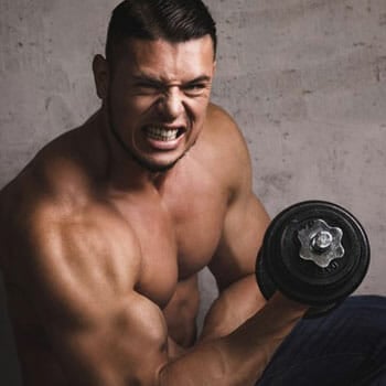 shirtless man doing a dumbbell workout