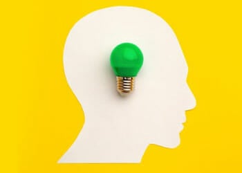 white silhouette of a head and a green light bulb on it