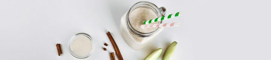 mason jar filled with protein shake with ingredients scattered beside it