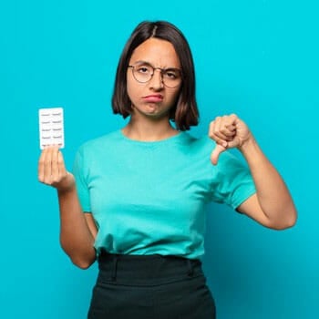 woman holding a sheet of pills with her thumbs down