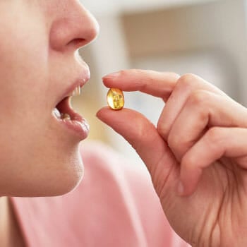 person drinking a fish oil capsule