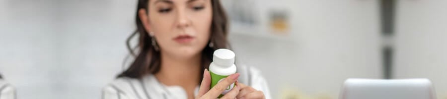 woman holding up a bottle pill and reading its label