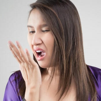 woman smelling her breath with her hands