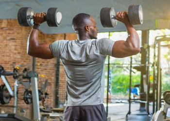 A man in the gym using dumbbells to workout chest and triceps