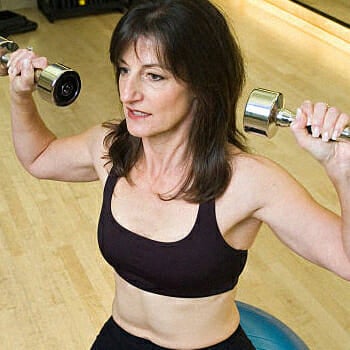 Middle aged woman doing overhead press workout