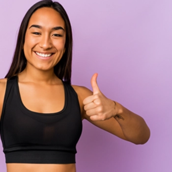 woman in a gym raising a thumbs up after workout