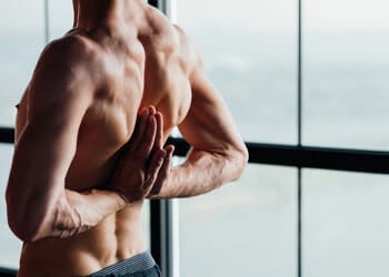 shirtless man flexing his back muscles