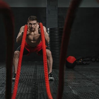 shirtless man doing high intensity workout with a rope