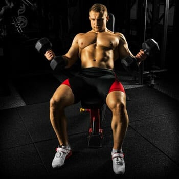 shirtless man doing dumbbell flyes in an incline bench