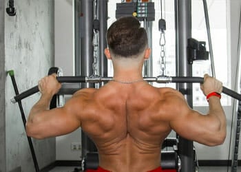 man using a lat machine shirtless