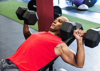 man doing dumbbell pressed in a gym