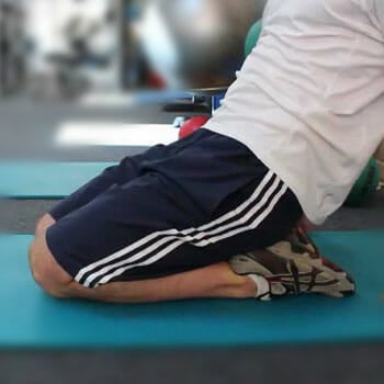 man kneeling on his feet in gym clothes