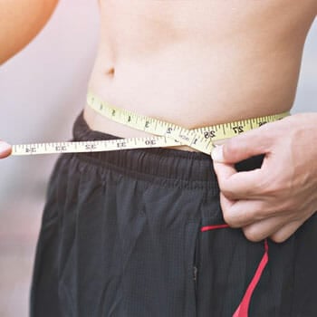 man using a measuring tape on his bare stomach