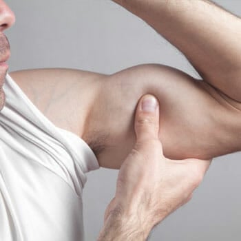 man flexing and squeezing his biceps using his hands